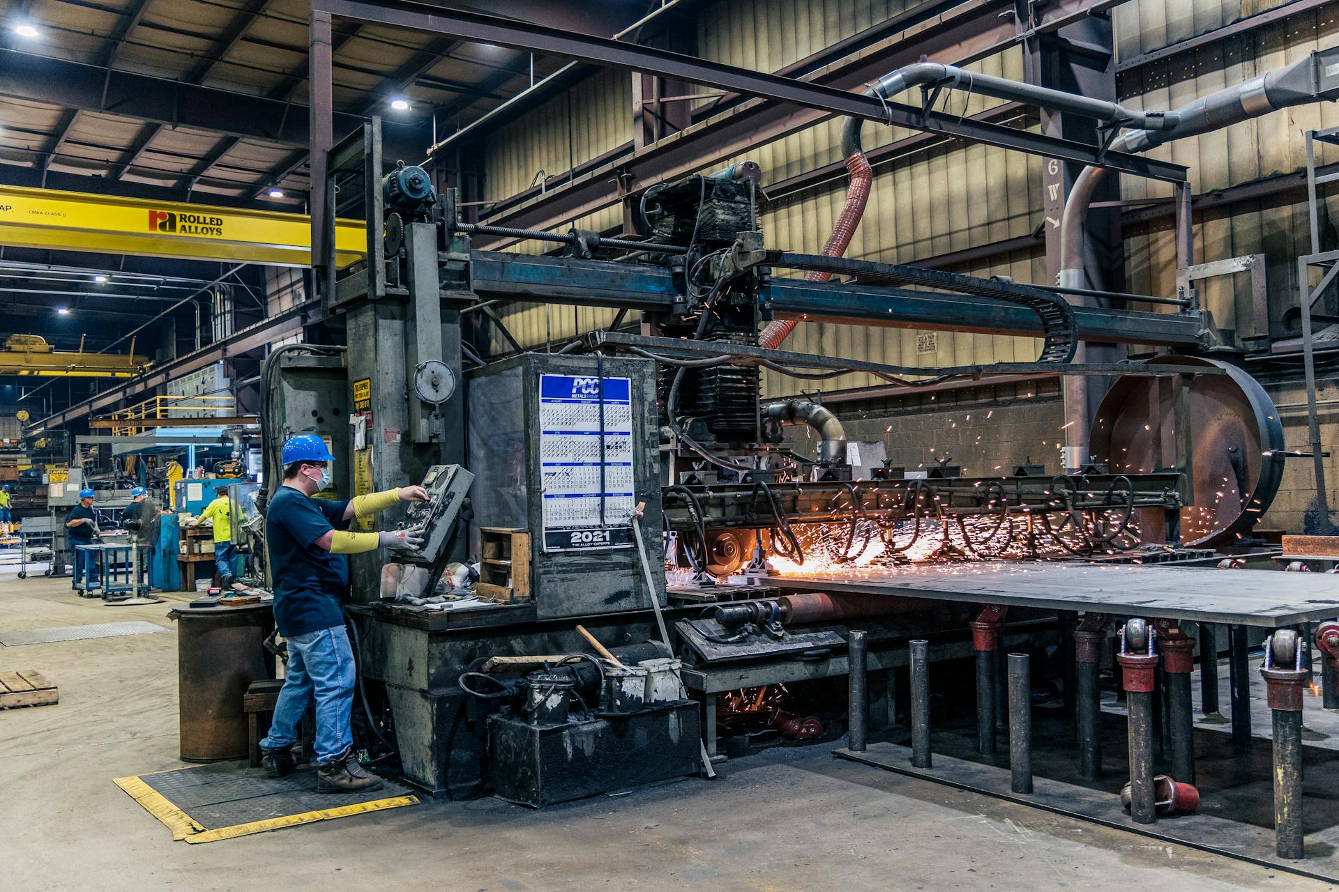 Operator standing next to a fastener-production machine on the shop floor