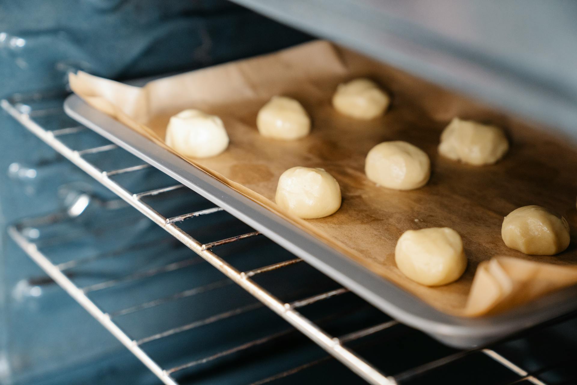 Rounded dough portions arranged on a baking tray inside an industrial oven