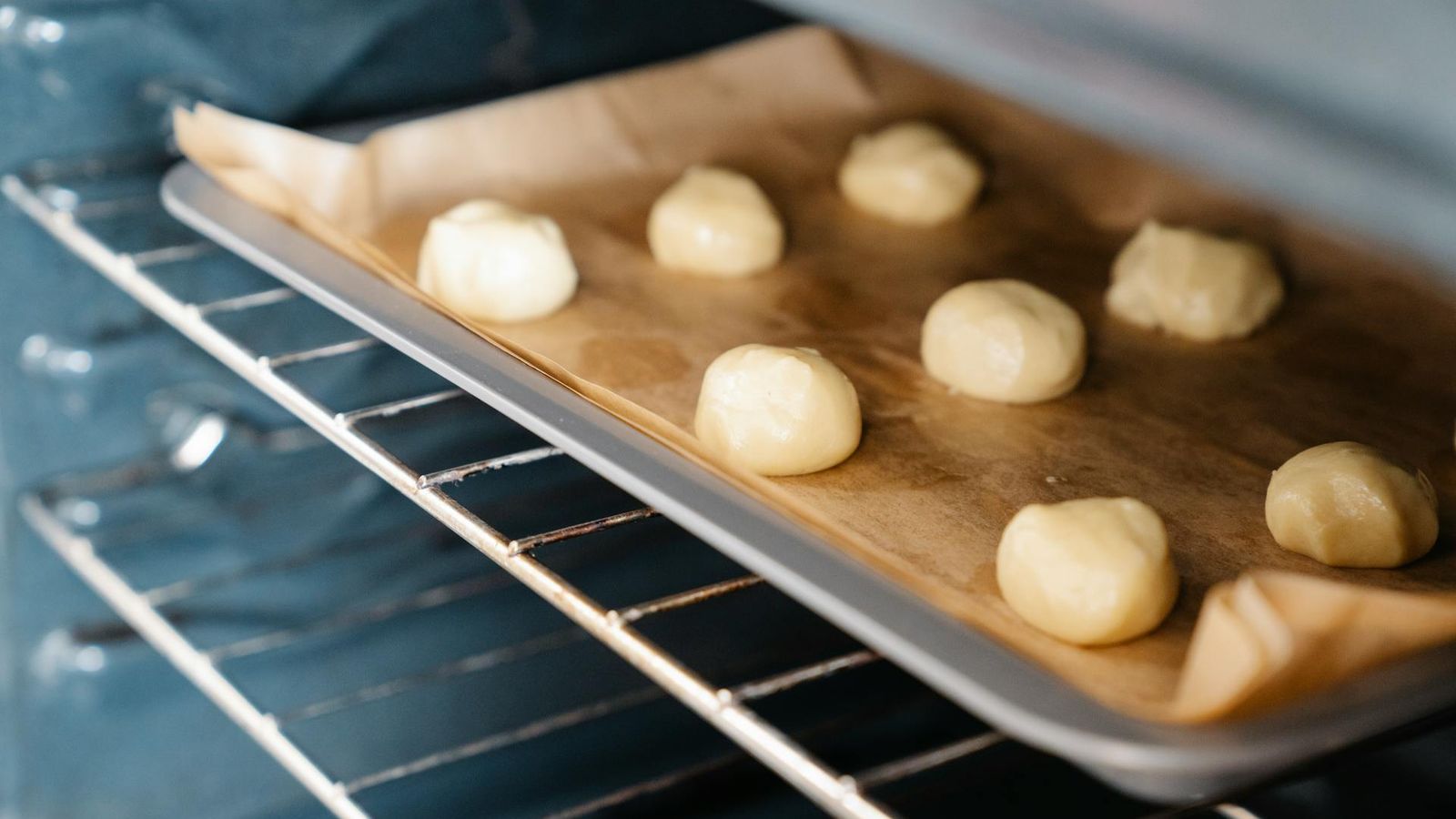 Rounded dough portions arranged on a baking tray inside an industrial oven