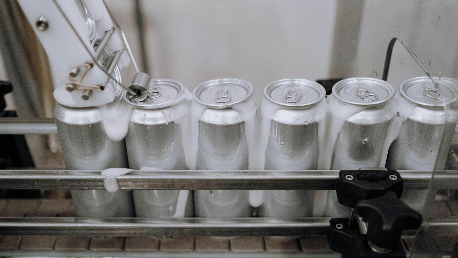 Latas de alumínio a serem cheias e capsuladas numa linha de produção de bebidas