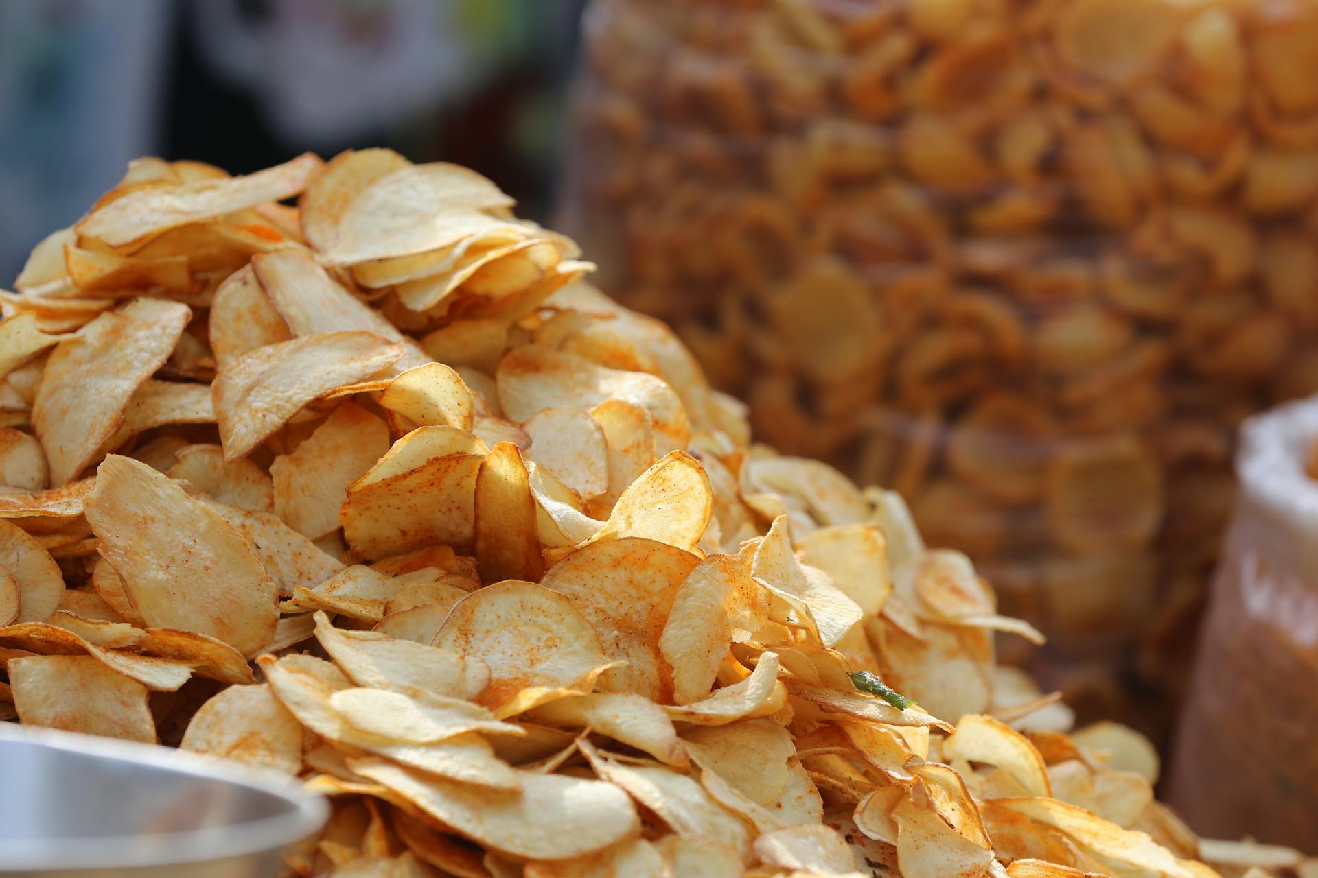 Pile of fried potato chips with golden-brown colour variation and broken pieces