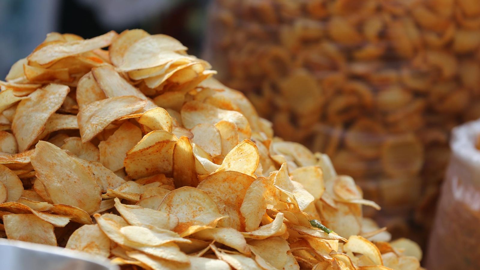 Pile of fried potato chips with golden-brown colour variation and broken pieces