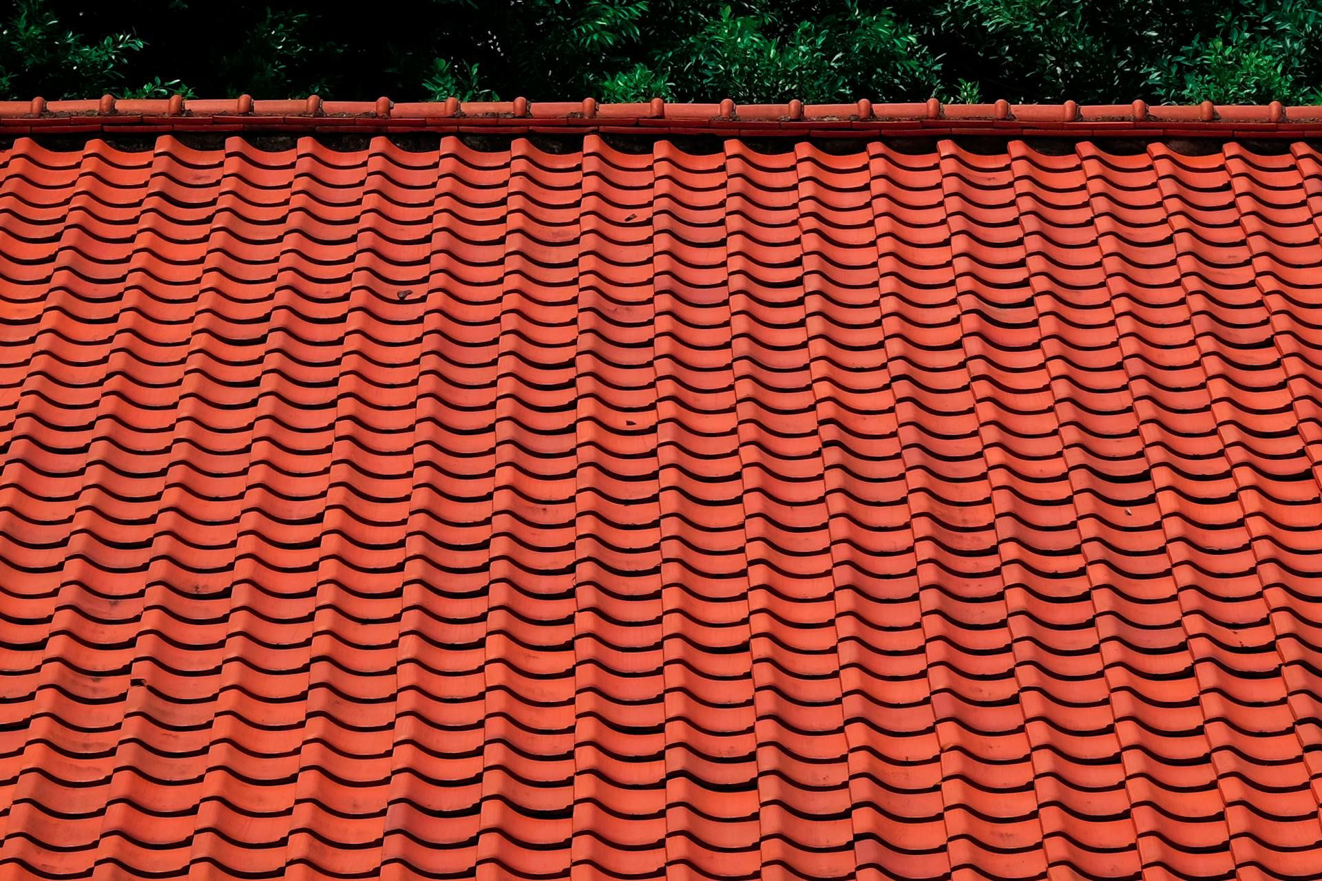 Gros plan de tuiles rouges en céramique posées en rangées régulières sur une toiture résidentielle