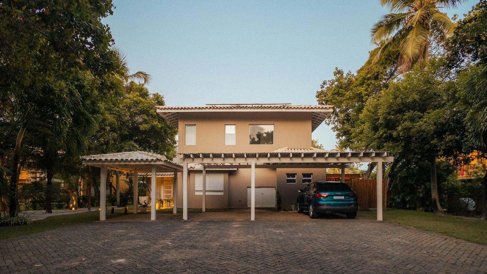 Rumah dua lantai dengan carport dan pepohonan (ilustrasi)
