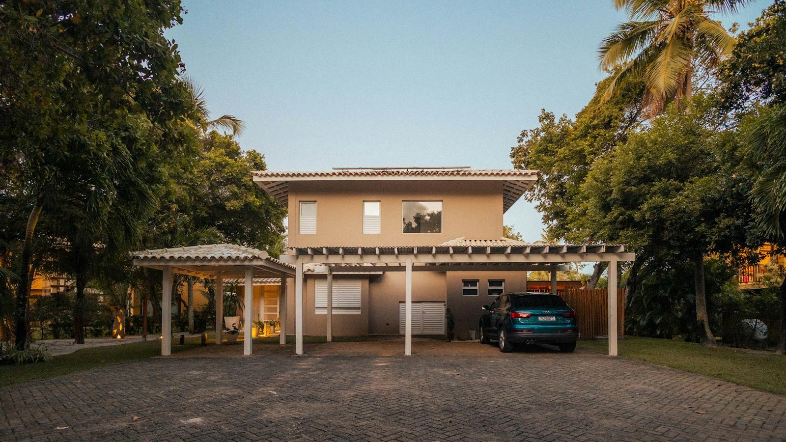 Rumah dua lantai dengan carport dan pepohonan (ilustrasi)
