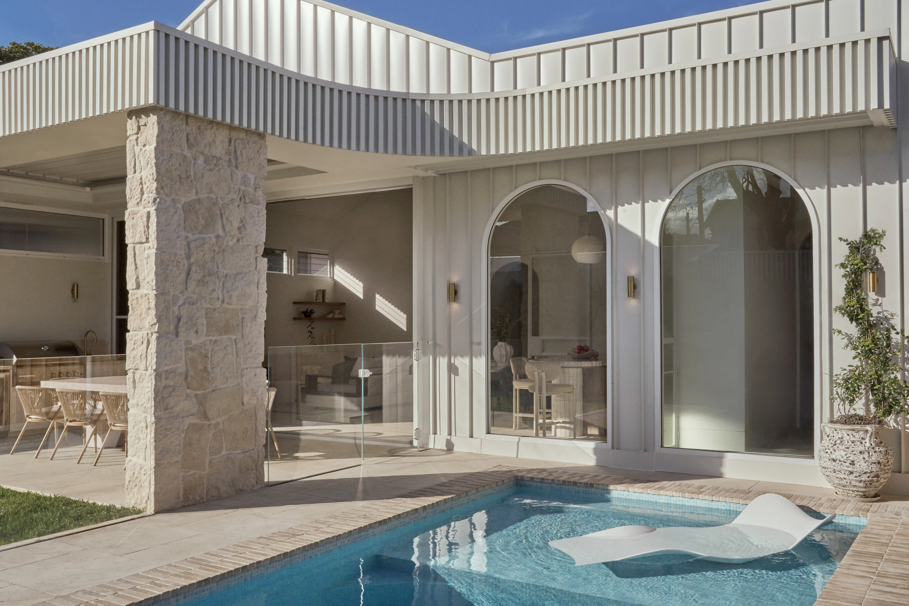 CONWAY rear extension in Randwick with arched windows beside a pool and stone column.