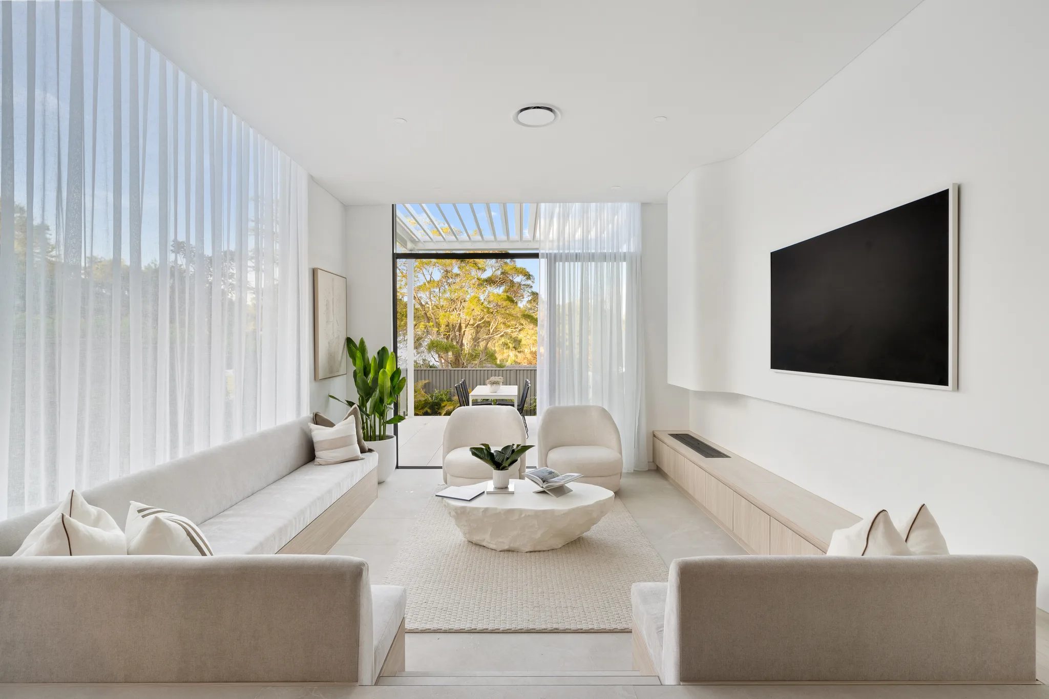 Sunken living room at LIME in North Ryde with built-in seating and tall sheer curtains.