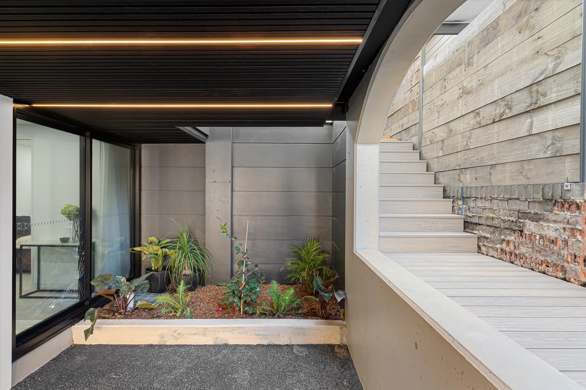 Courtyard at CLAY in Rozelle with garden beds and steps beside off-form concrete walls.