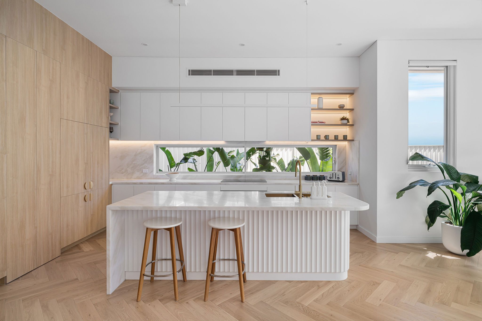 LATTICE's kitchen in Matraville, a fluted island and timber joinery beneath a window splashback