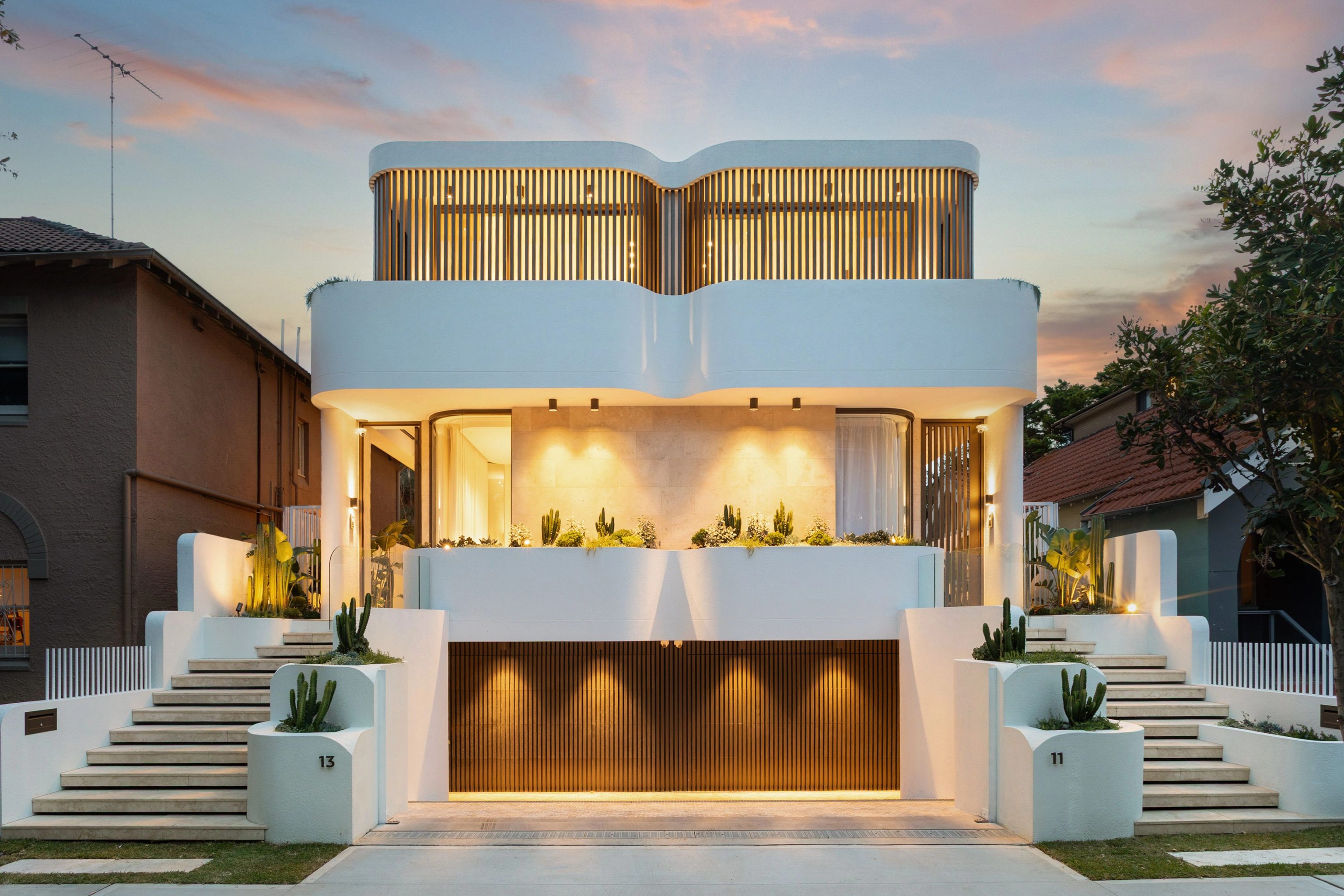 SOL Bondi Beach duplex street facade at dusk with curved white render and timber battens