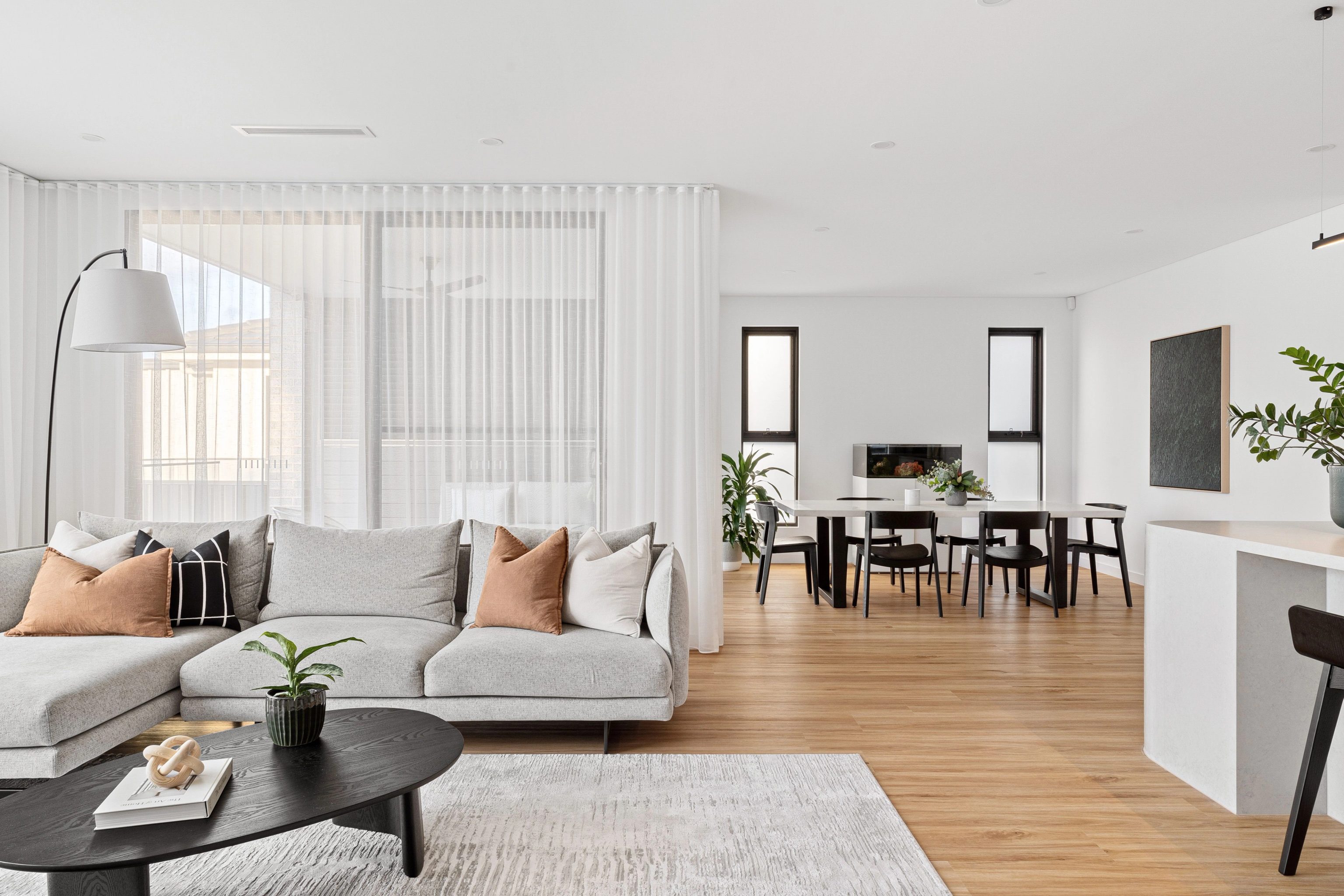 ELBA living and dining room in Pagewood with a pale sofa, timber floors and sheer curtains.
