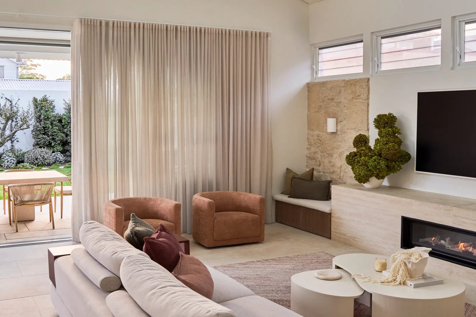 CONWAY living room with a stone fireplace and doors opening to the Randwick home's garden