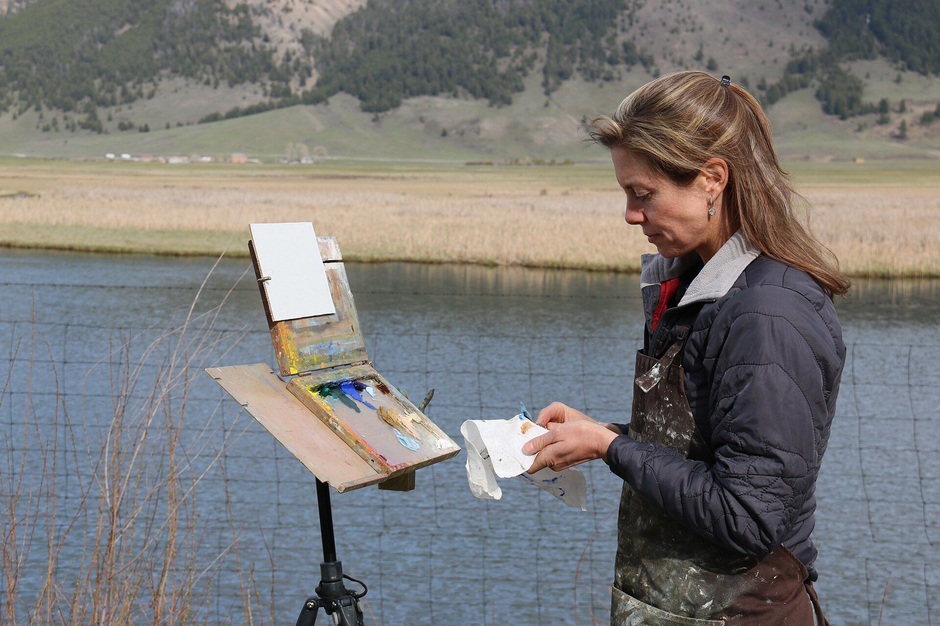 A painter preparing paints for a plein-air session beside Flat Creek