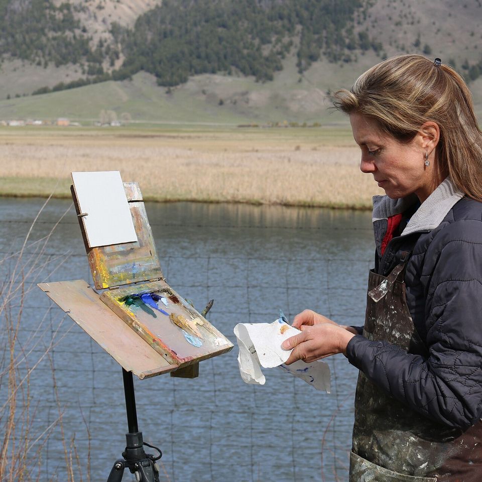 A painter preparing paints for a plein-air session beside Flat Creek