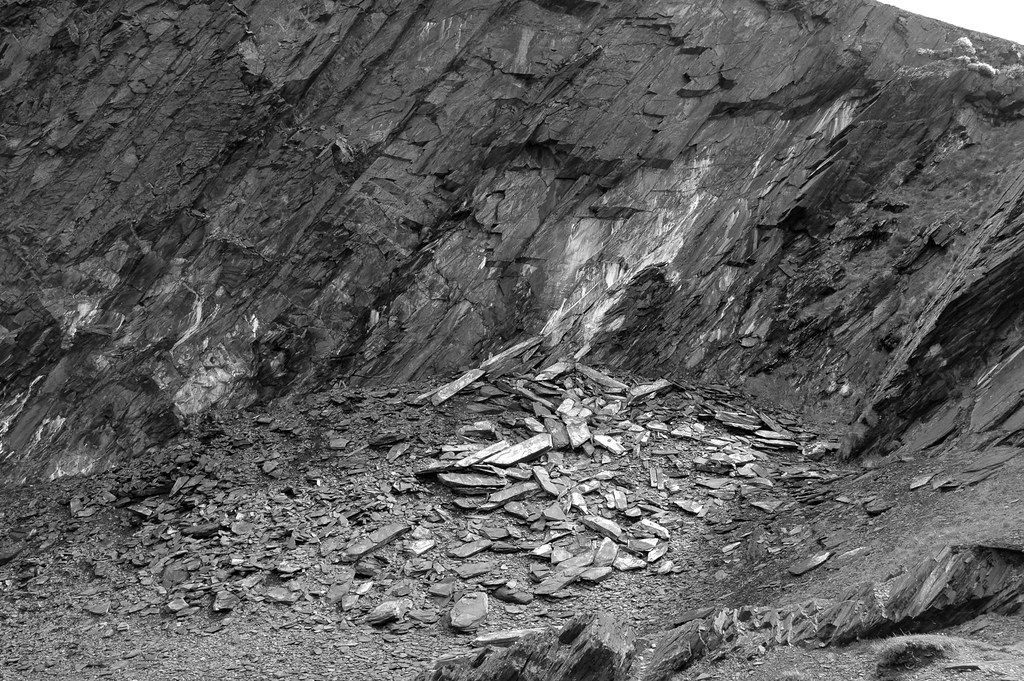 Coastal abandoned slate quarry with rocky cliffs and a path leading toward the sea