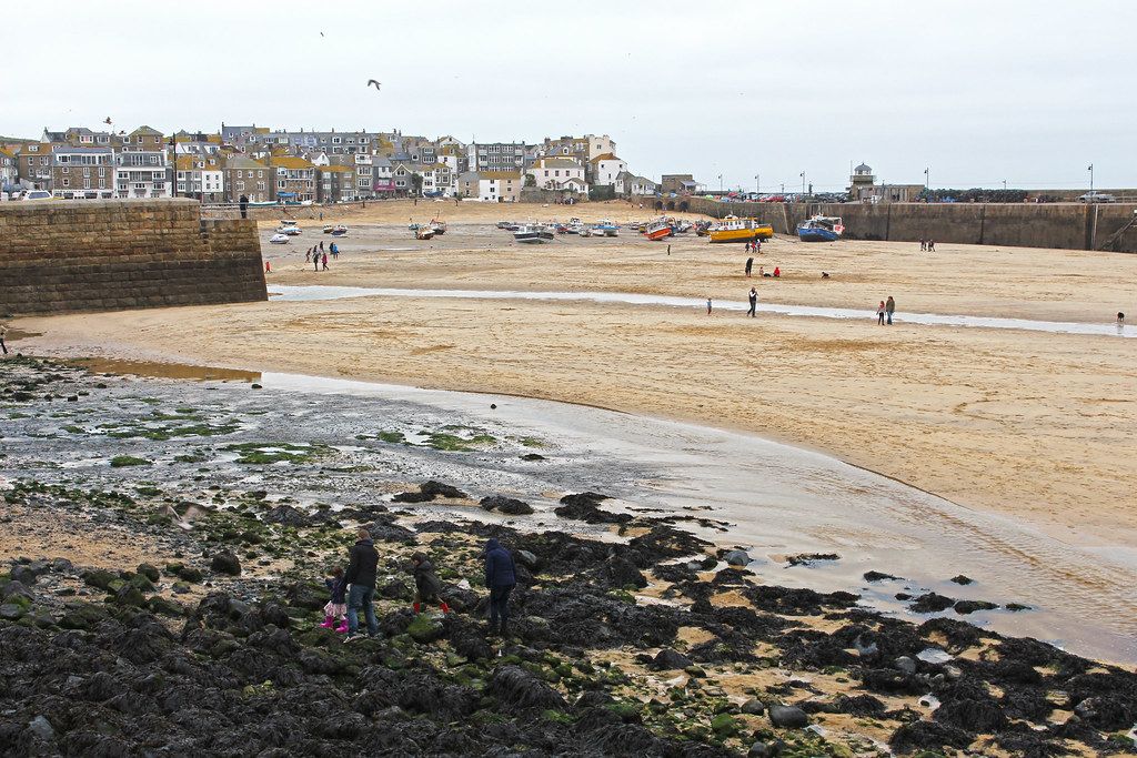 St. Ives harbour at low tide with boats resting on exposed sand and the coastal shoreline visible