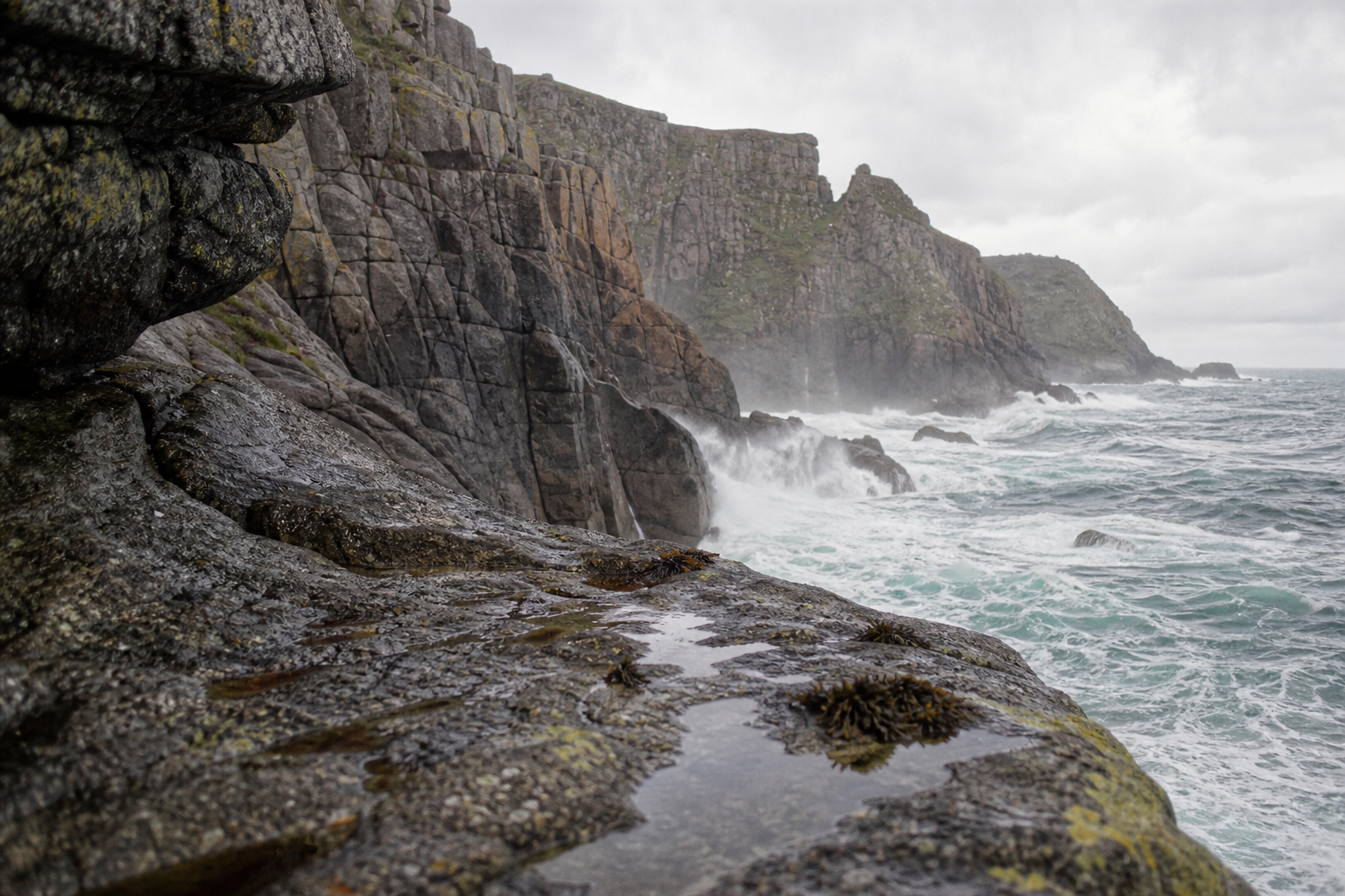 Rugged granite cliffs above Atlantic surf on a bright overcast day