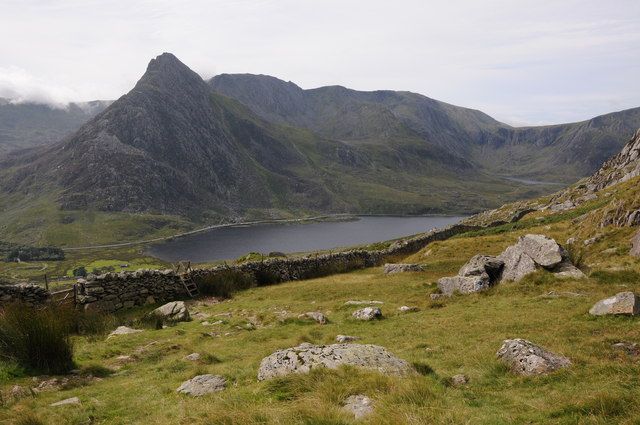 Llyn Ogwen lake in a valley with Tryfan mountain and grassy, heather-covered slopes under a frosty sky