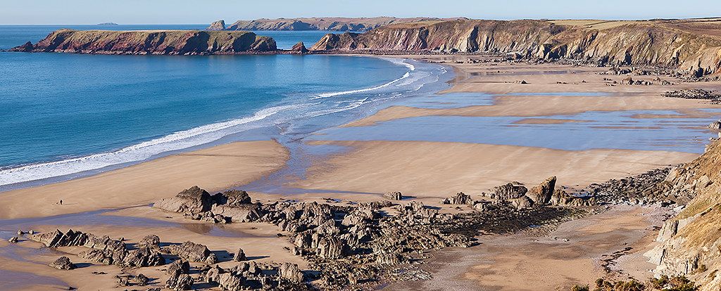 Sandy beach and rocky coastline at Marloes Sands with a coastal path and sea in Pembrokeshire