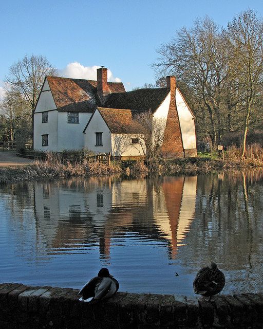 Millpond with a traditional riverside house and winter sky reflected in the water