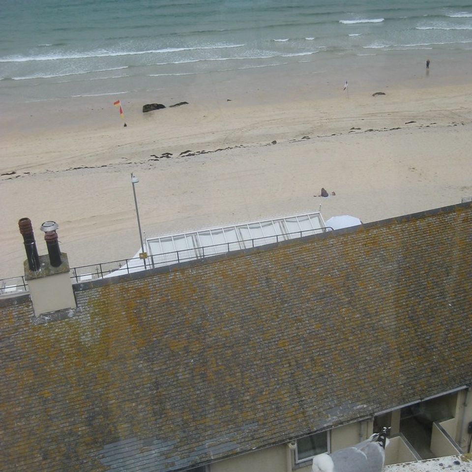 Coastal view from a cafe overlooking a beach, ocean, and nearby buildings in St Ives, Cornwall.