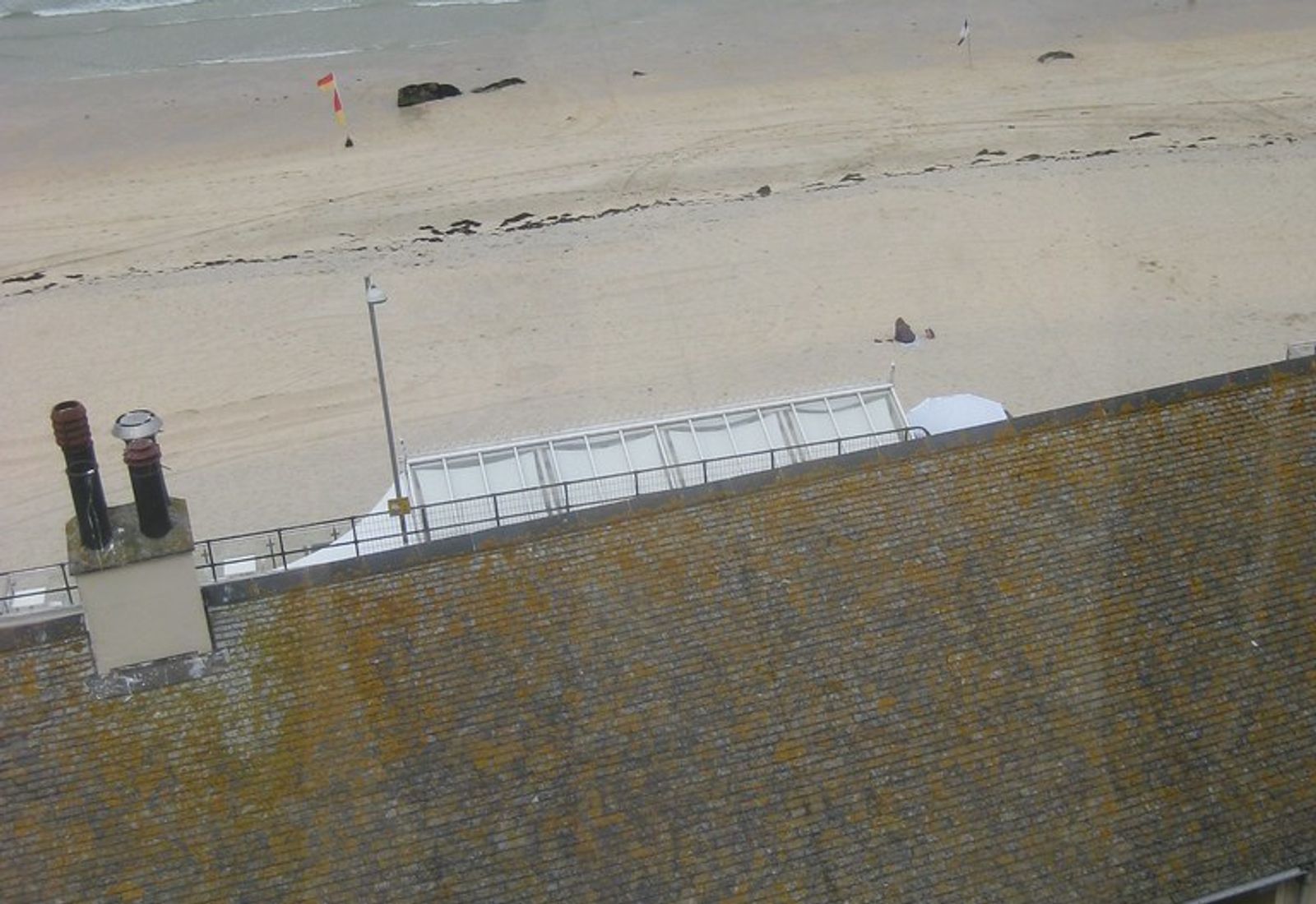 Coastal view from a cafe overlooking a beach, ocean, and nearby buildings in St Ives, Cornwall.