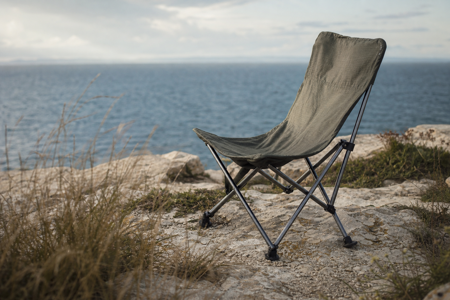 Small folding ultralight chair on coastal cliffs with sea and sky beyond