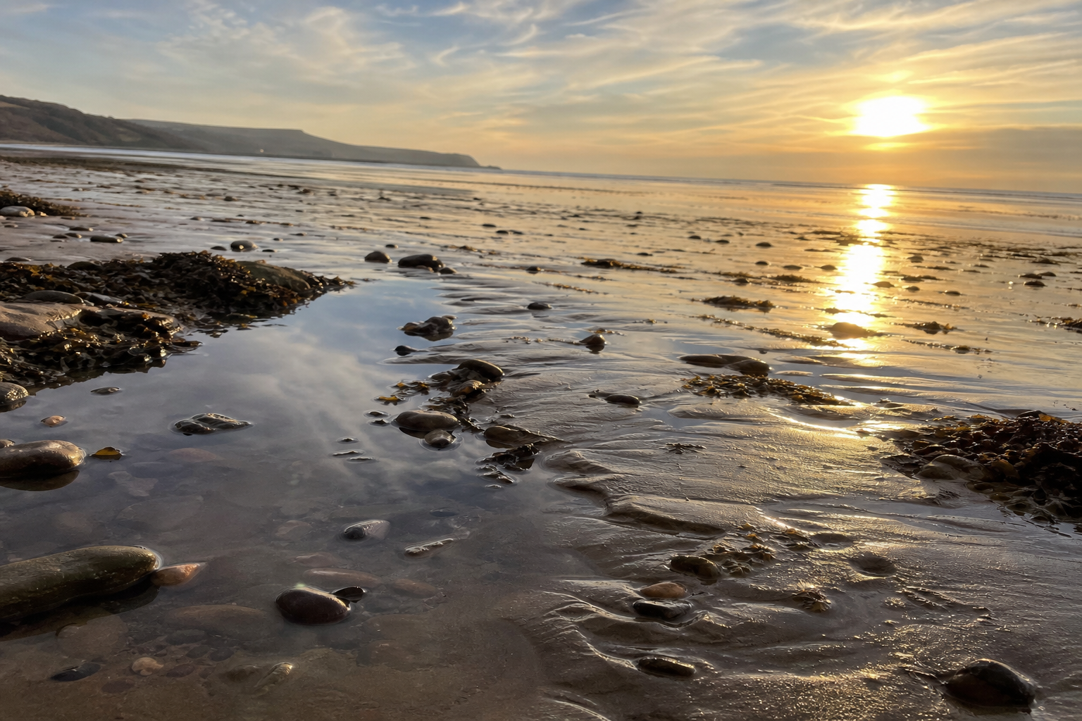 Wet sand reflecting golden late afternoon light at a low tide UK beach
