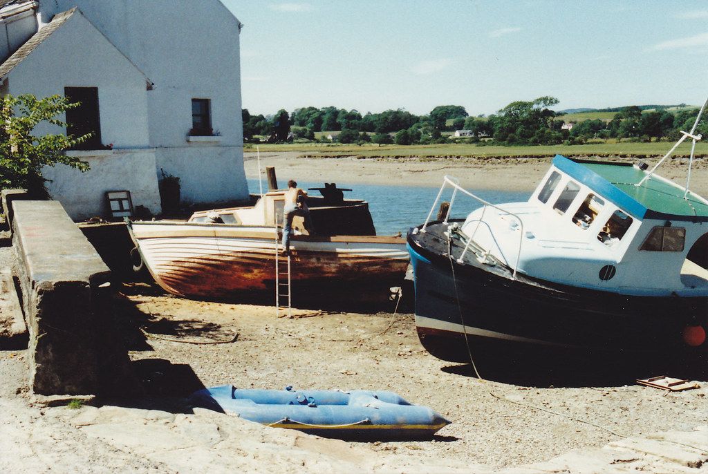 Harbour with moored boats and a house on the waterfront in Kirkcudbright.
