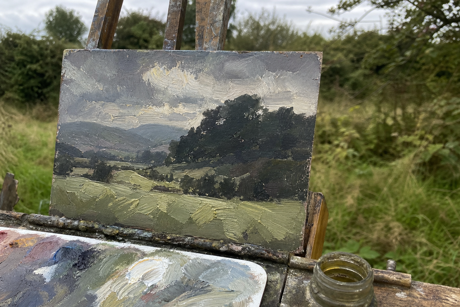 Small oil painting panel with bold brushstrokes, landscape subject, leaning on an easel