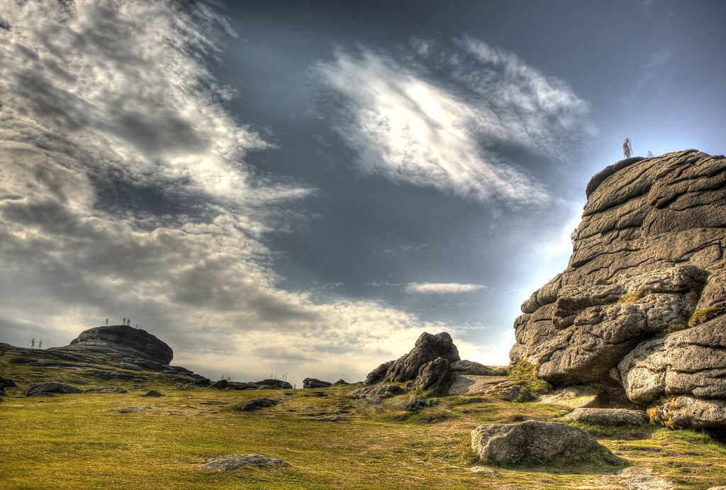Hay Tor granite rock formation rising above moorland with hills and a cloudy sky