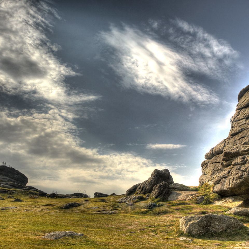 Hay Tor granite rock formation rising above moorland with hills and a cloudy sky