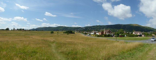 Rolling grassy hills and fields under a partly cloudy sky in the Malvern Hills