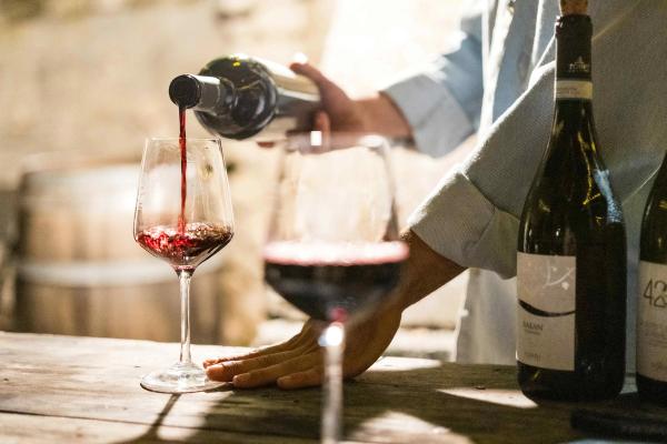 Red wine being poured into a wine glass on a wooden table.