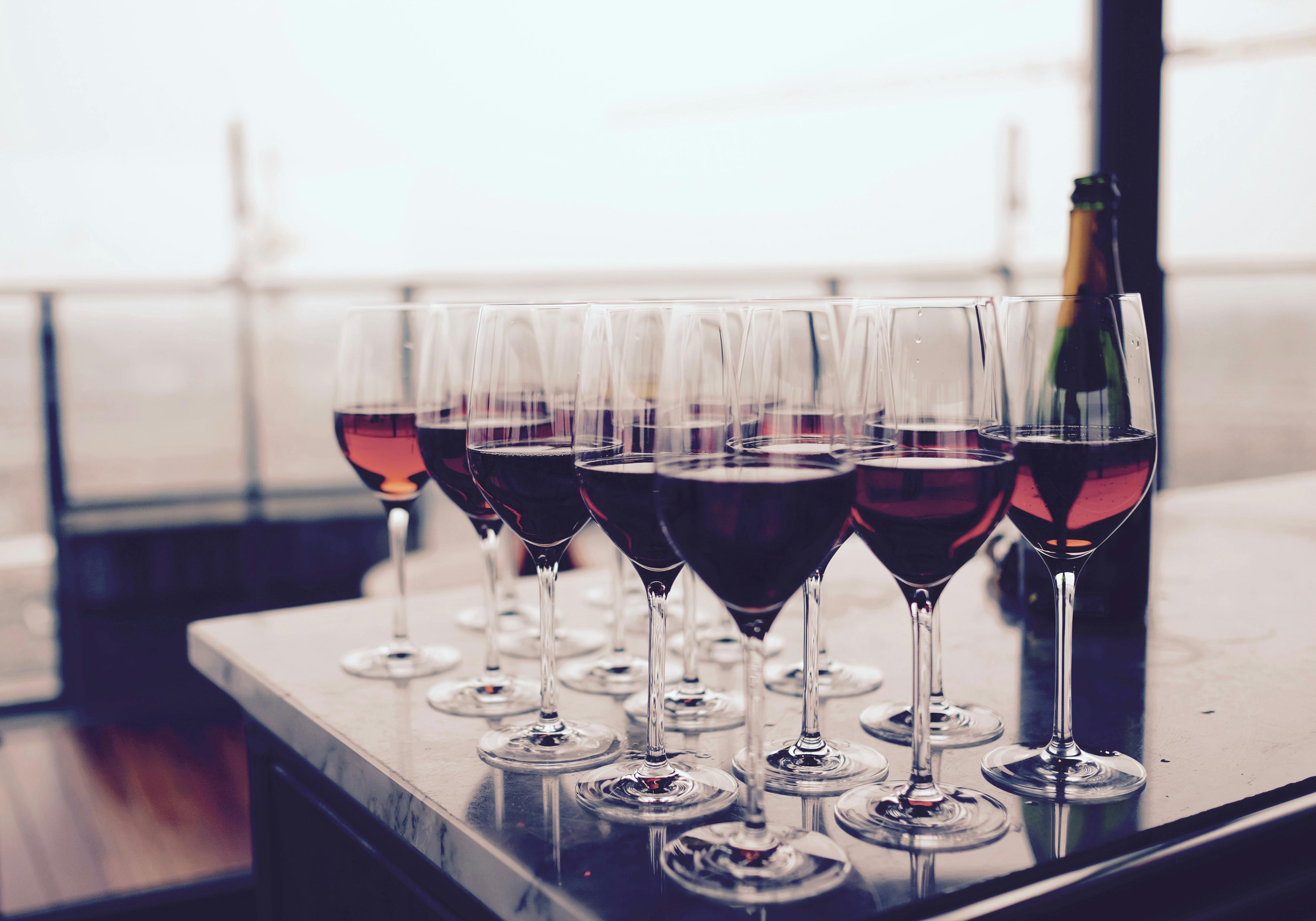 Sixteen full glasses of red wine resting on a kitchen island.
