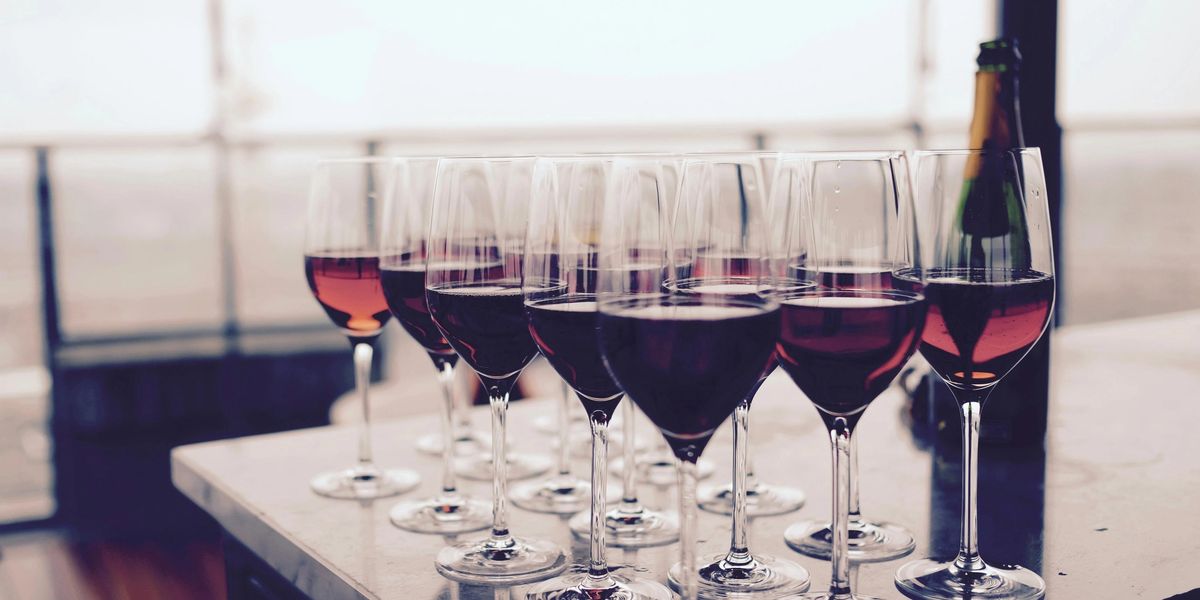 Sixteen full glasses of red wine resting on a kitchen island.