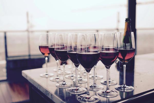 Sixteen full glasses of red wine resting on a kitchen island.