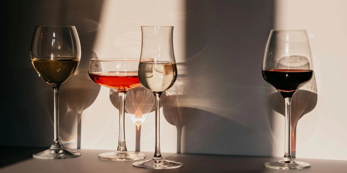 Four differently-shaped wine glasses full of different types of wine.