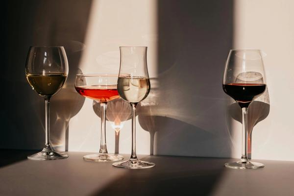 Four differently-shaped wine glasses full of different types of wine.
