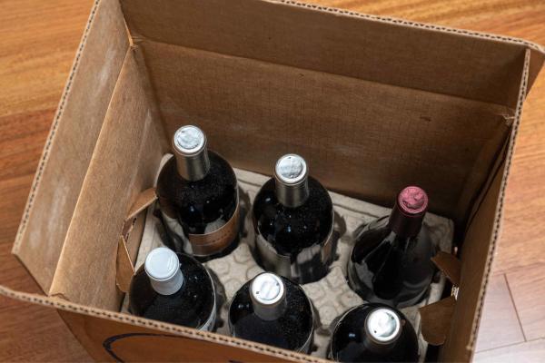 A shipping box containing six bottles of red wine.