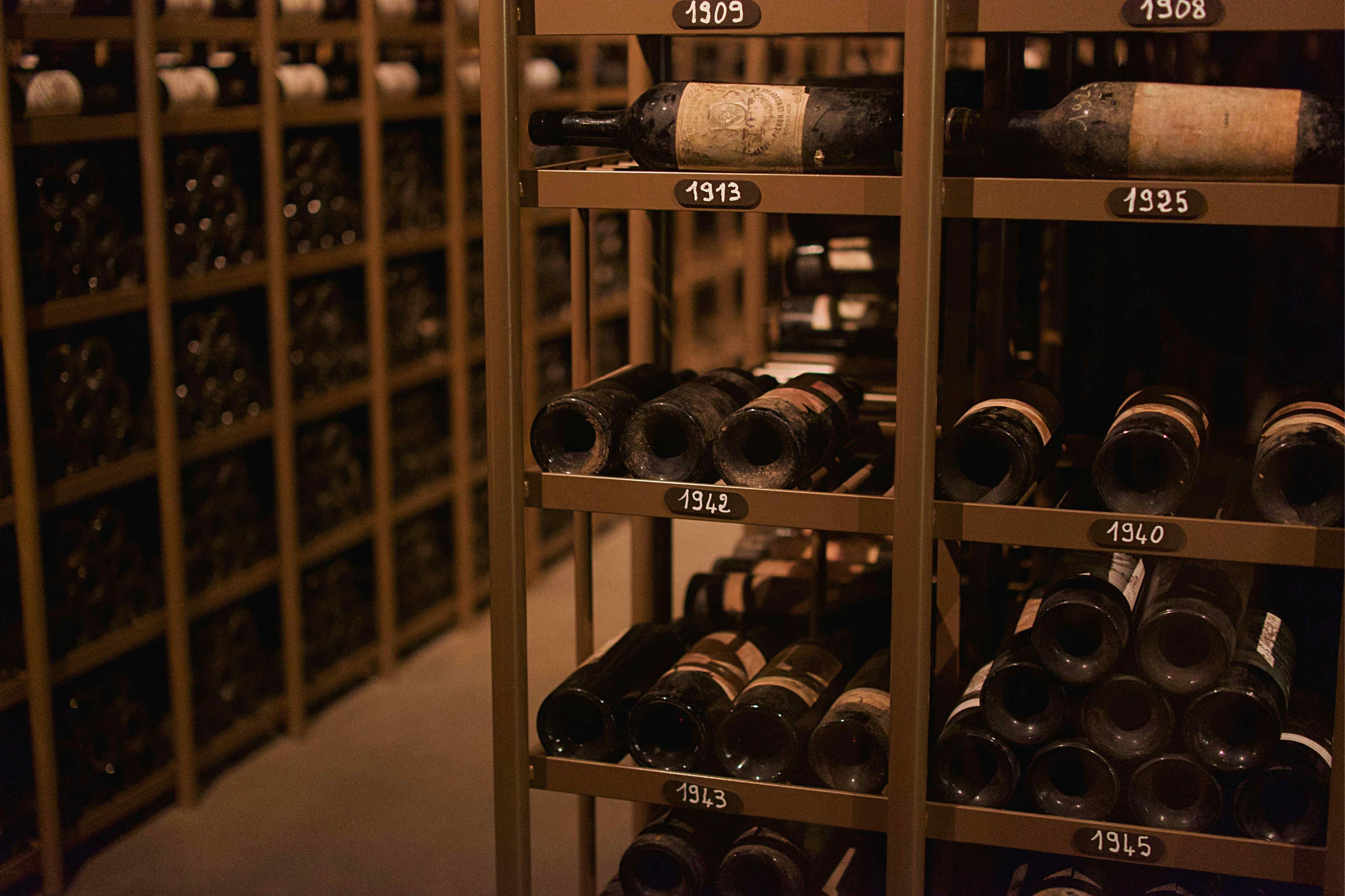 Professional wine cellar racking with vintage-labeled shelves from 1908 to 1945 holding dusty aged bottles.