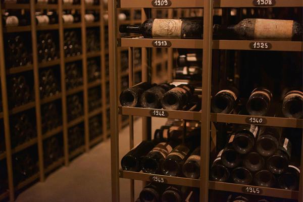 Professional wine cellar racking with vintage-labeled shelves from 1908 to 1945 holding dusty aged bottles.