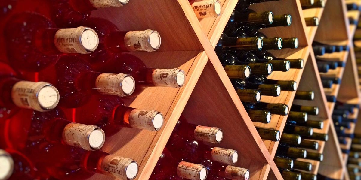 Diamond-shaped wooden wine rack cubbies holding red and dark green bottles with visible cork ends.
