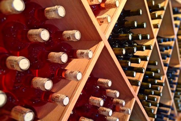 Diamond-shaped wooden wine rack cubbies holding red and dark green bottles with visible cork ends.