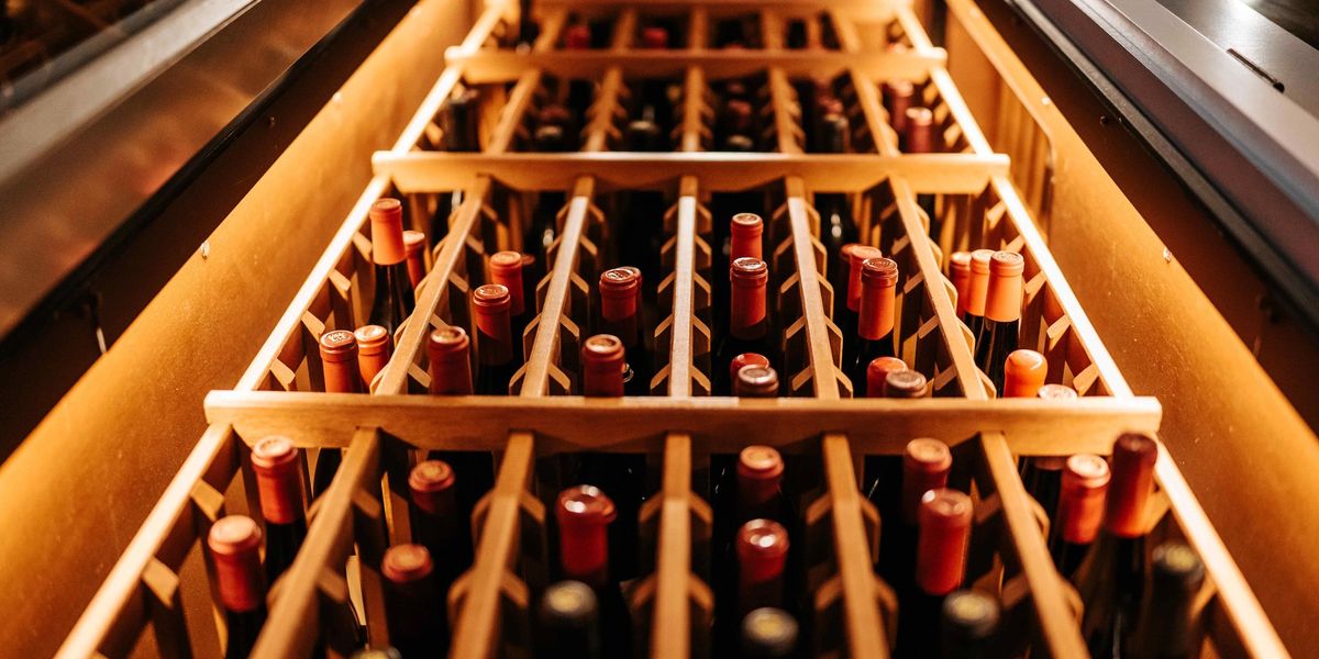 A wine fridge full of organized wine bottles.