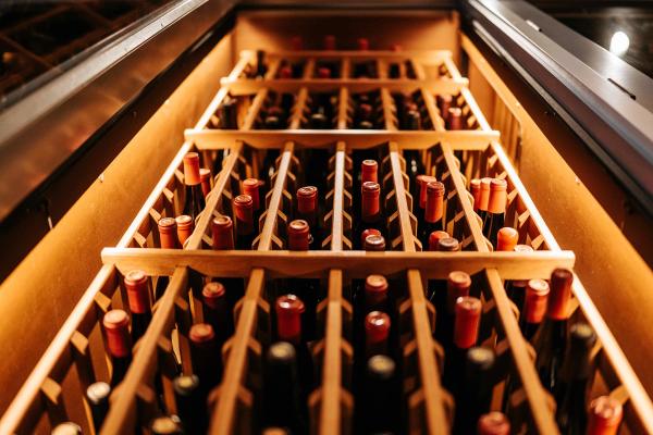 A wine fridge full of organized wine bottles.