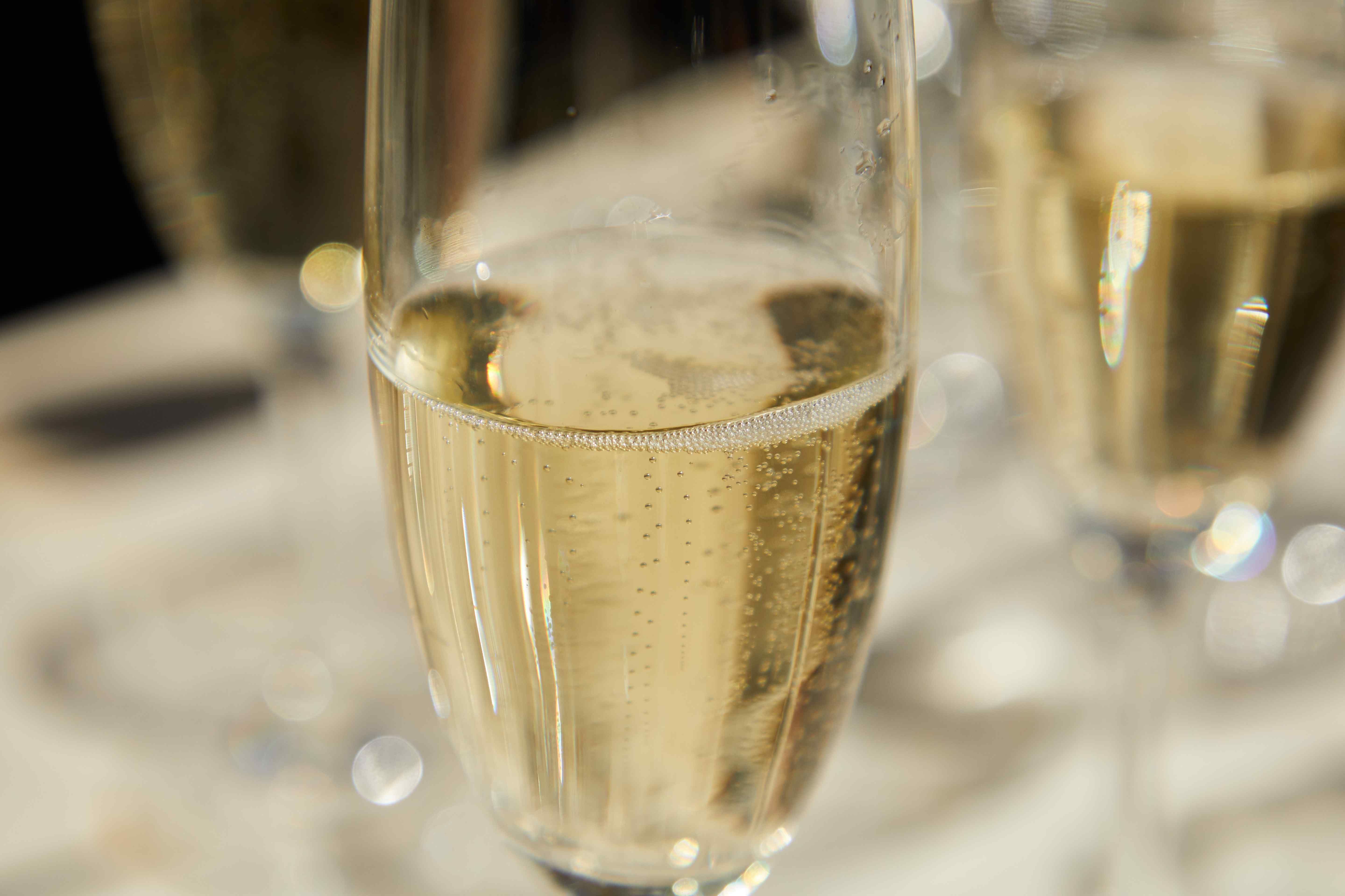 Close-up of a champagne flute filled with sparkling wine, showing rising bubbles.