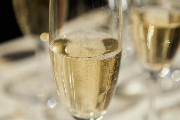 Close-up of a champagne flute filled with sparkling wine, showing rising bubbles.