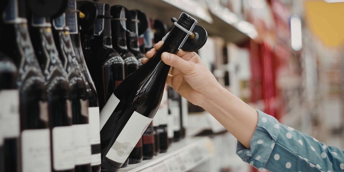 A red wine bottle being selected off the shelf at a wine shop.