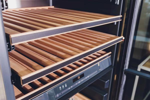 Open wine fridge shelf with wooden slats and a digital control panel displaying 16 degrees.